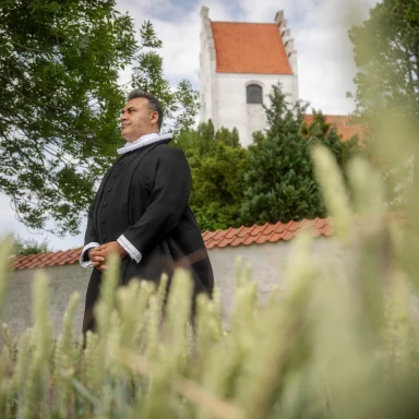 Naser Khader i sin præstekjole foran Fensmark Kirke